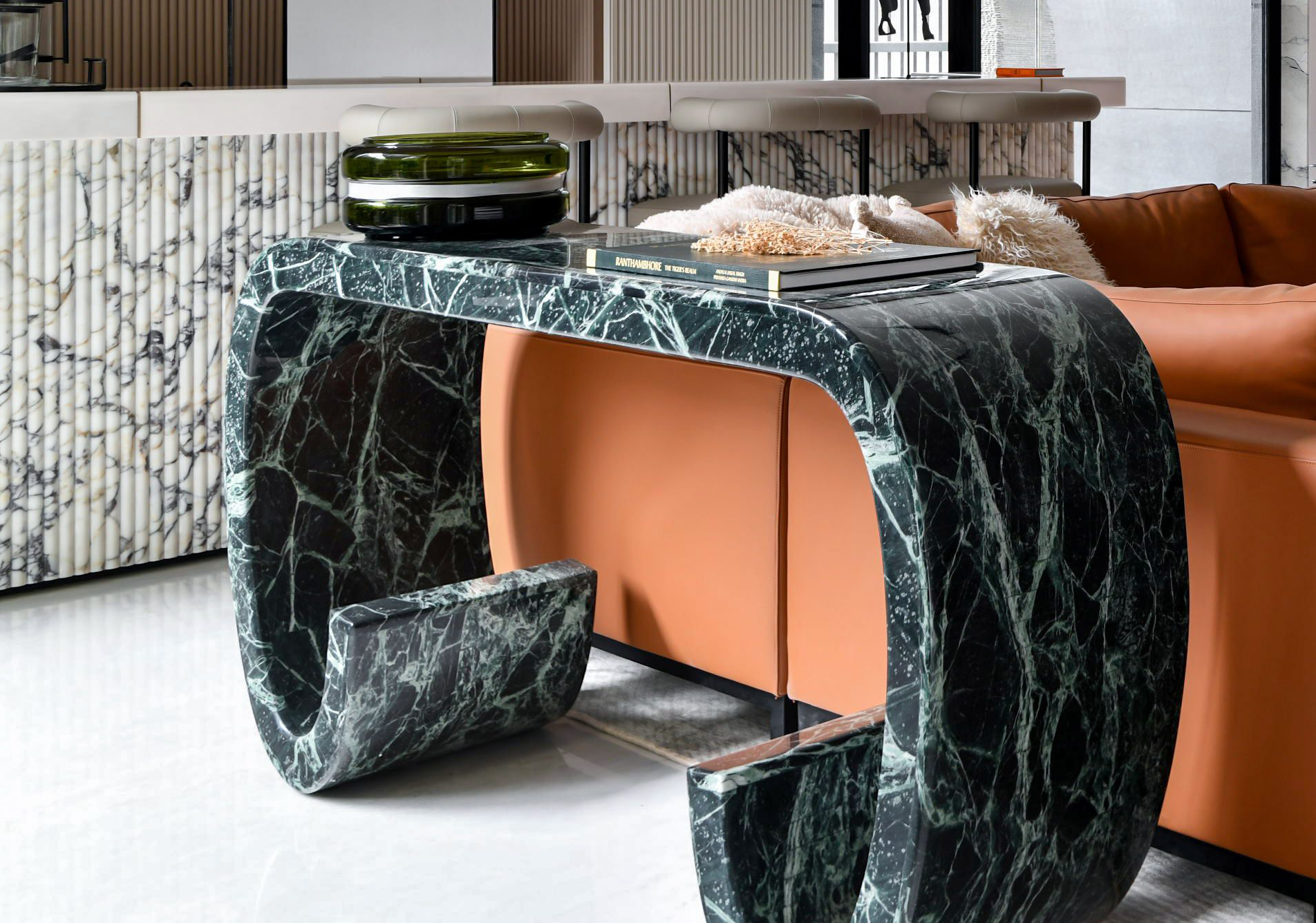 Mesa de apoio em mármore verde com veios, num espaço de estar com sofá castanho.